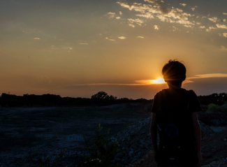 Child silhouetted looking at a sunset