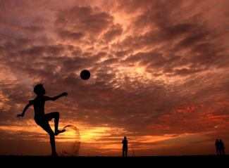 Child silhouetted playing with a ball